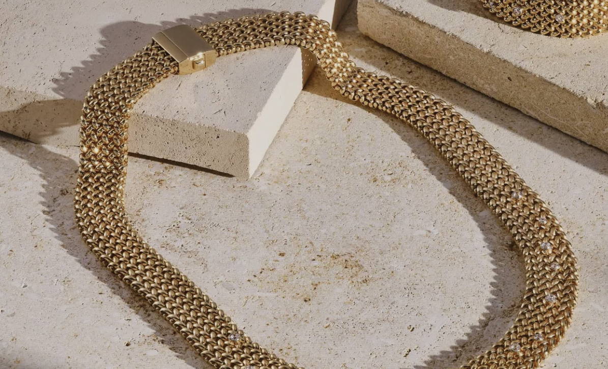 Een man draagt een vrouw op een onverharde weg in een bos. Zij glimlacht, hij kijkt de toeschouwer aan.