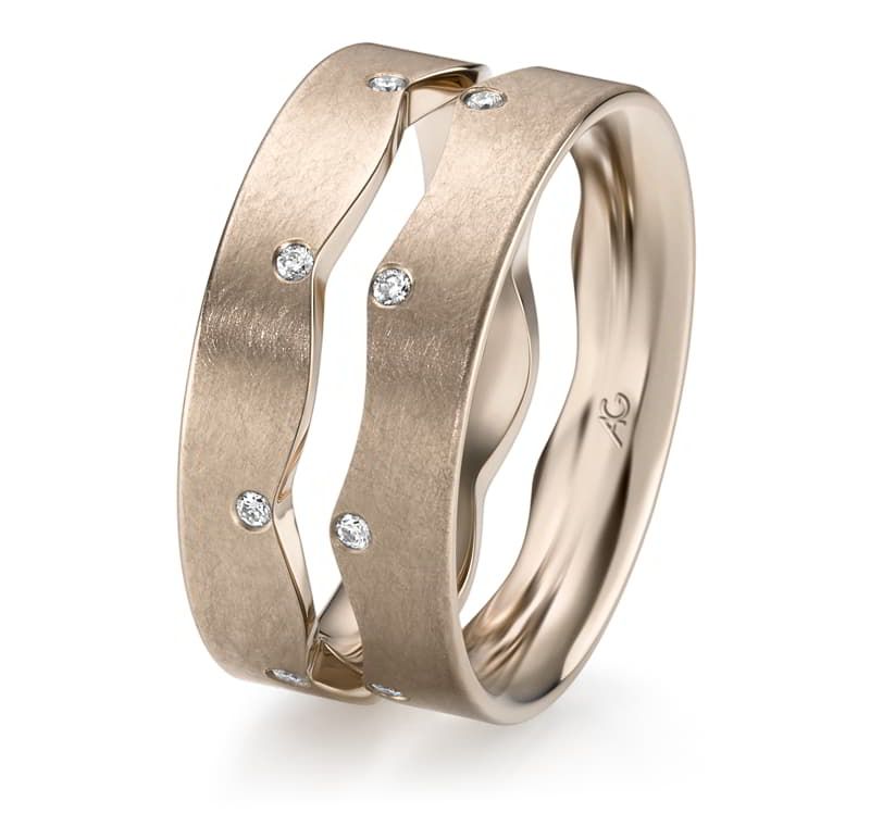 Twee gouden trouwringen met golvend ontwerp en ingelegde diamanten.