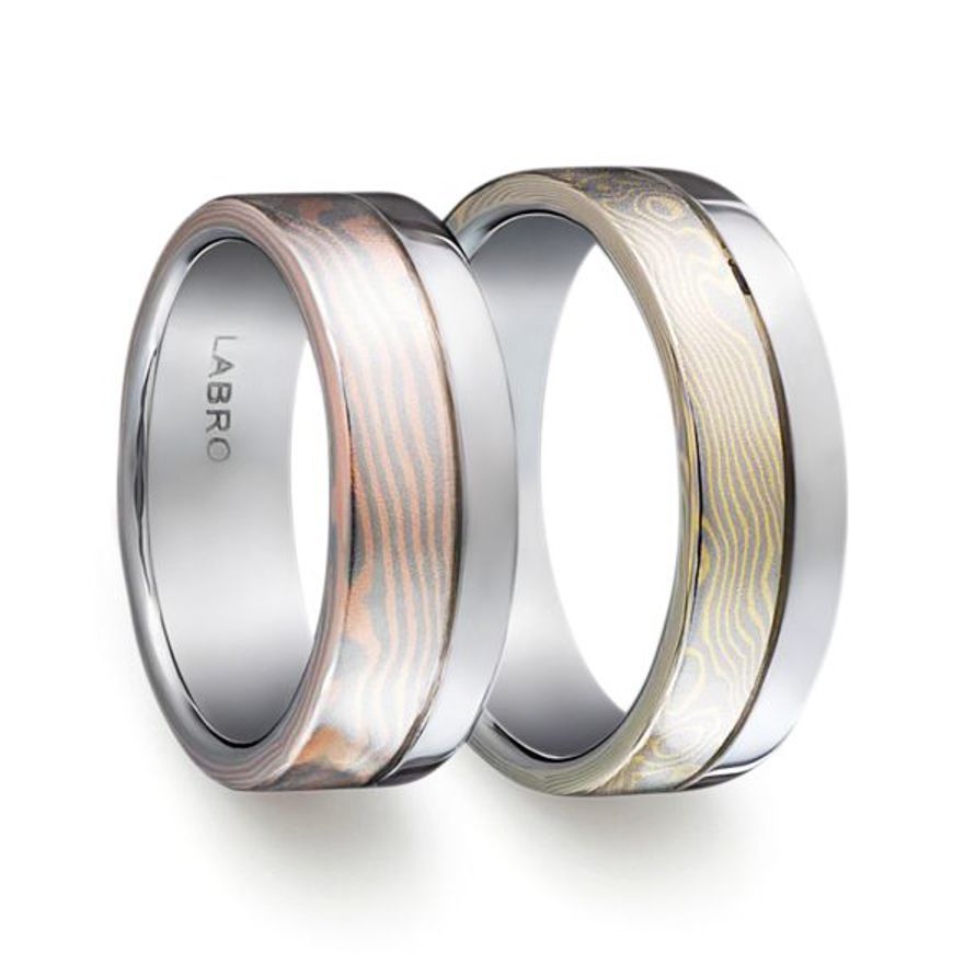 Gouden ring met vingerafdrukontwerp en kleine diamantjes op een gestructureerd oppervlak.