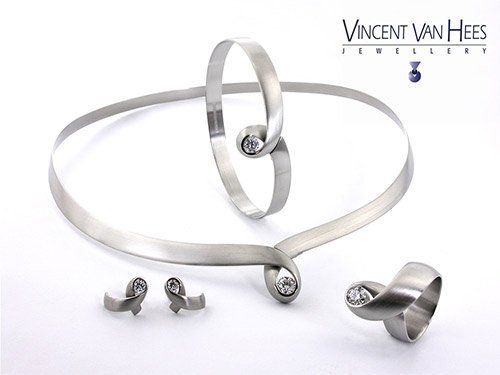 Set zilveren sieraden: ketting, armband, oorbellen en ring, allemaal met diamanten accenten en een oneindigheidsachtig ontwerp.