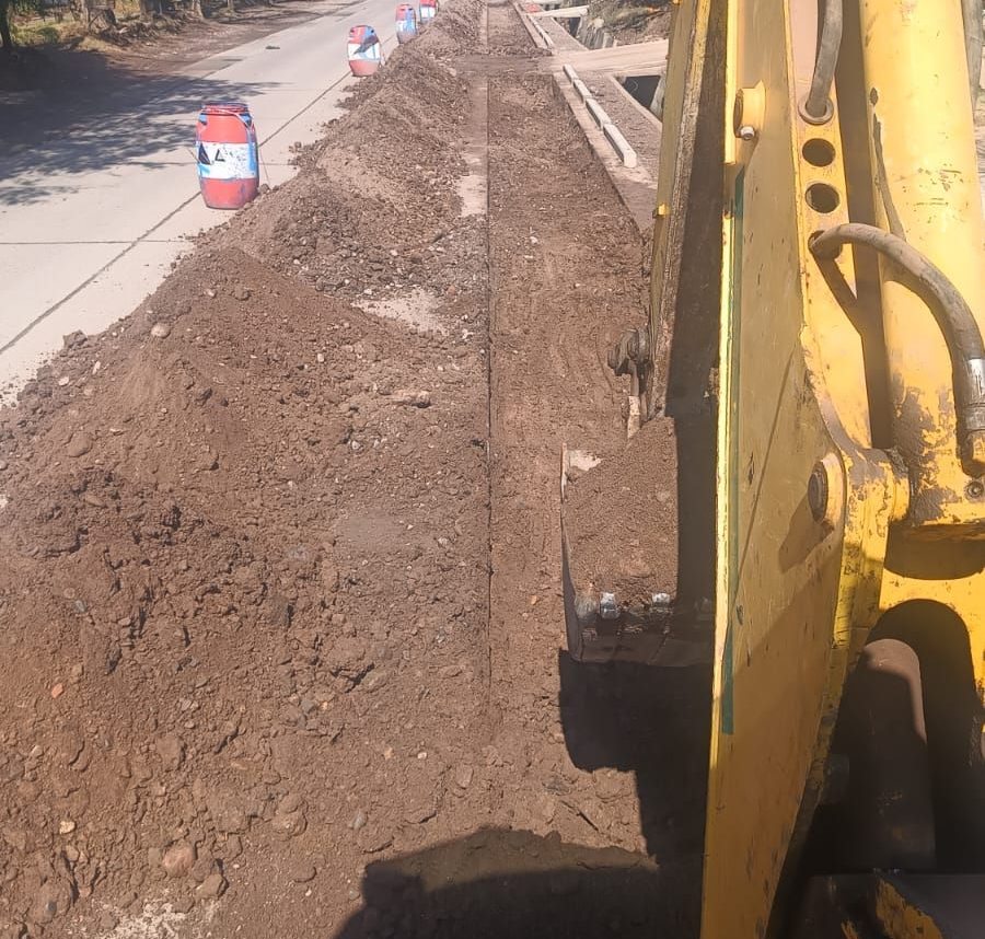 Excavadora azul con pinza de demolición demoliendo estructura de ladrillo.