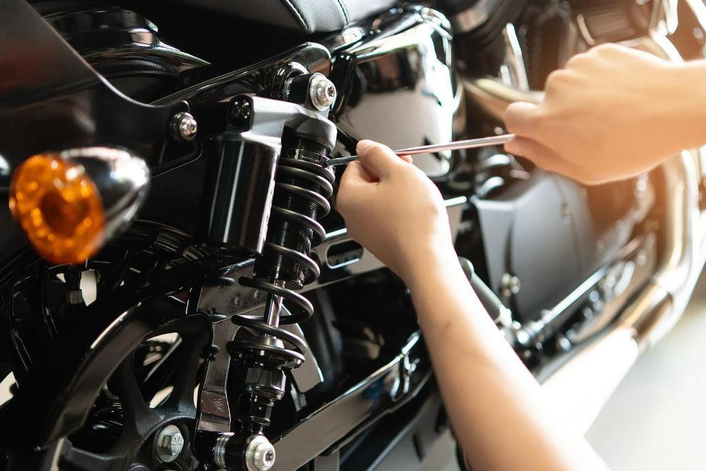 A Person Is Working on A Motorcycle with A Wrench — Currajong Brake Parts Pty Ltd In Currajong, QLD