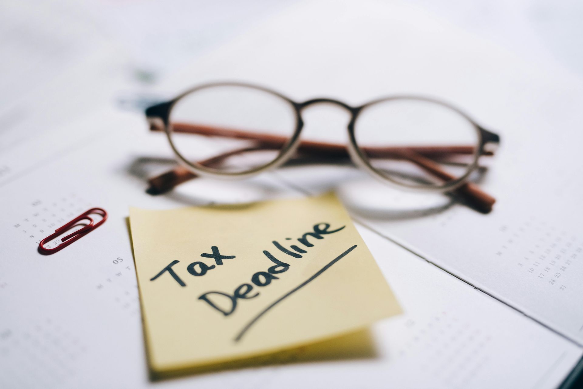 Sticky note with tax deadline, glasses and diary – bookkeeping and accounting deadline support for small businesses
