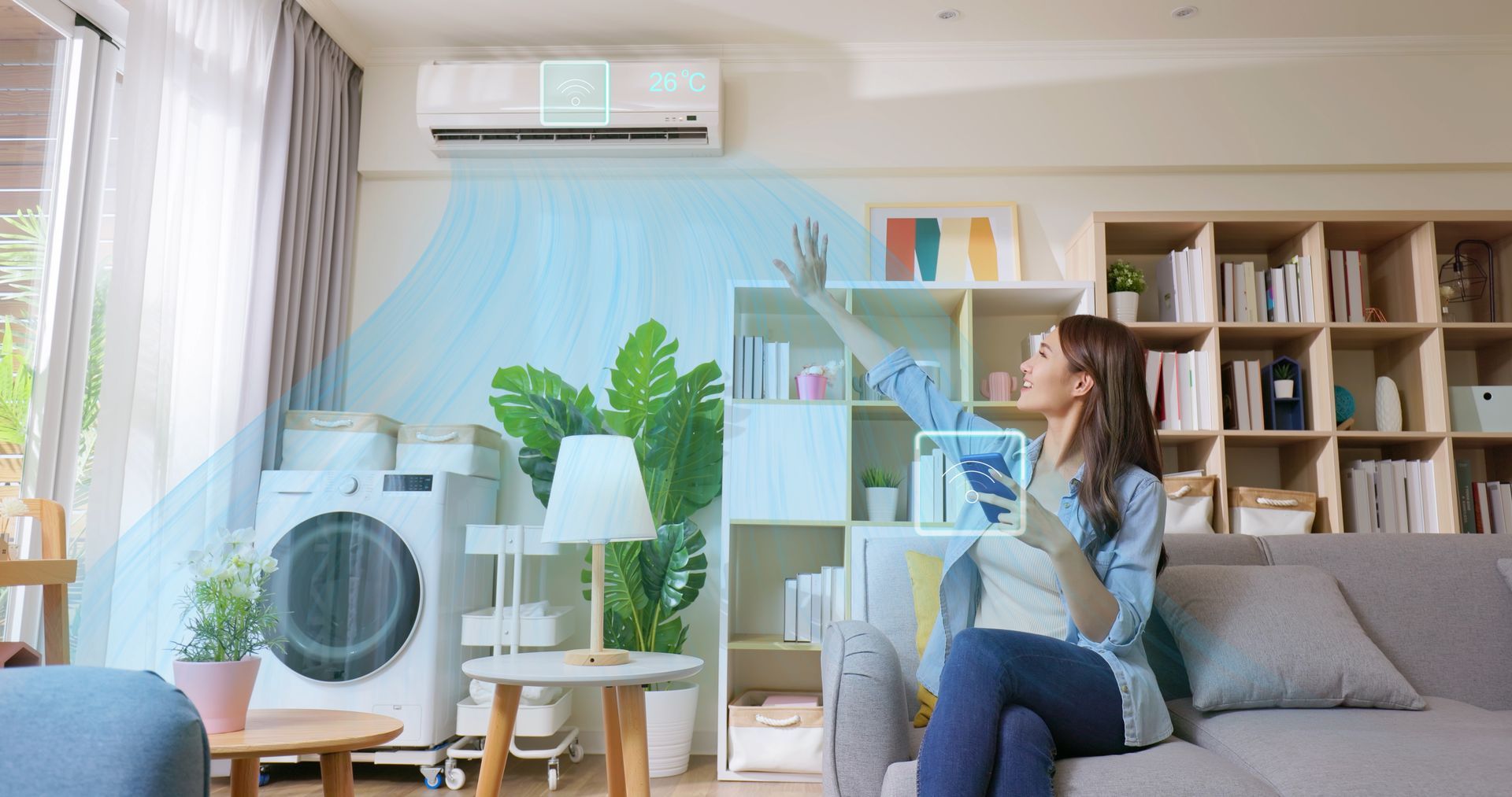 Woman using a tablet to control air conditioner in a living room; a washing machine is visible.