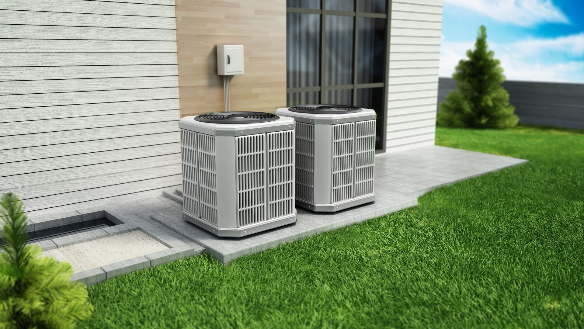 Two air conditioning units on a concrete pad near a house with green lawn and blue sky.
