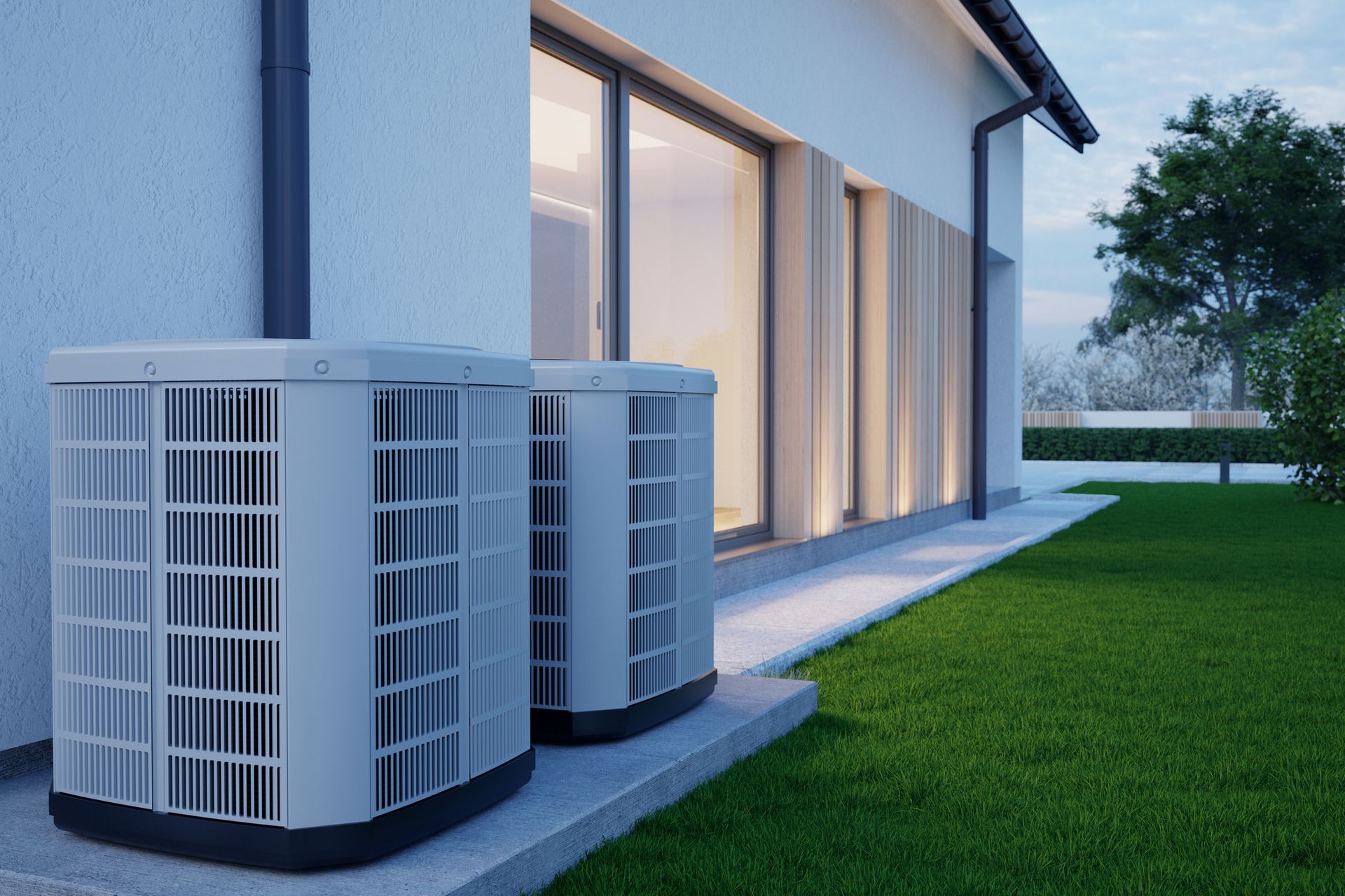 Two air conditioning units beside a house on a green lawn.