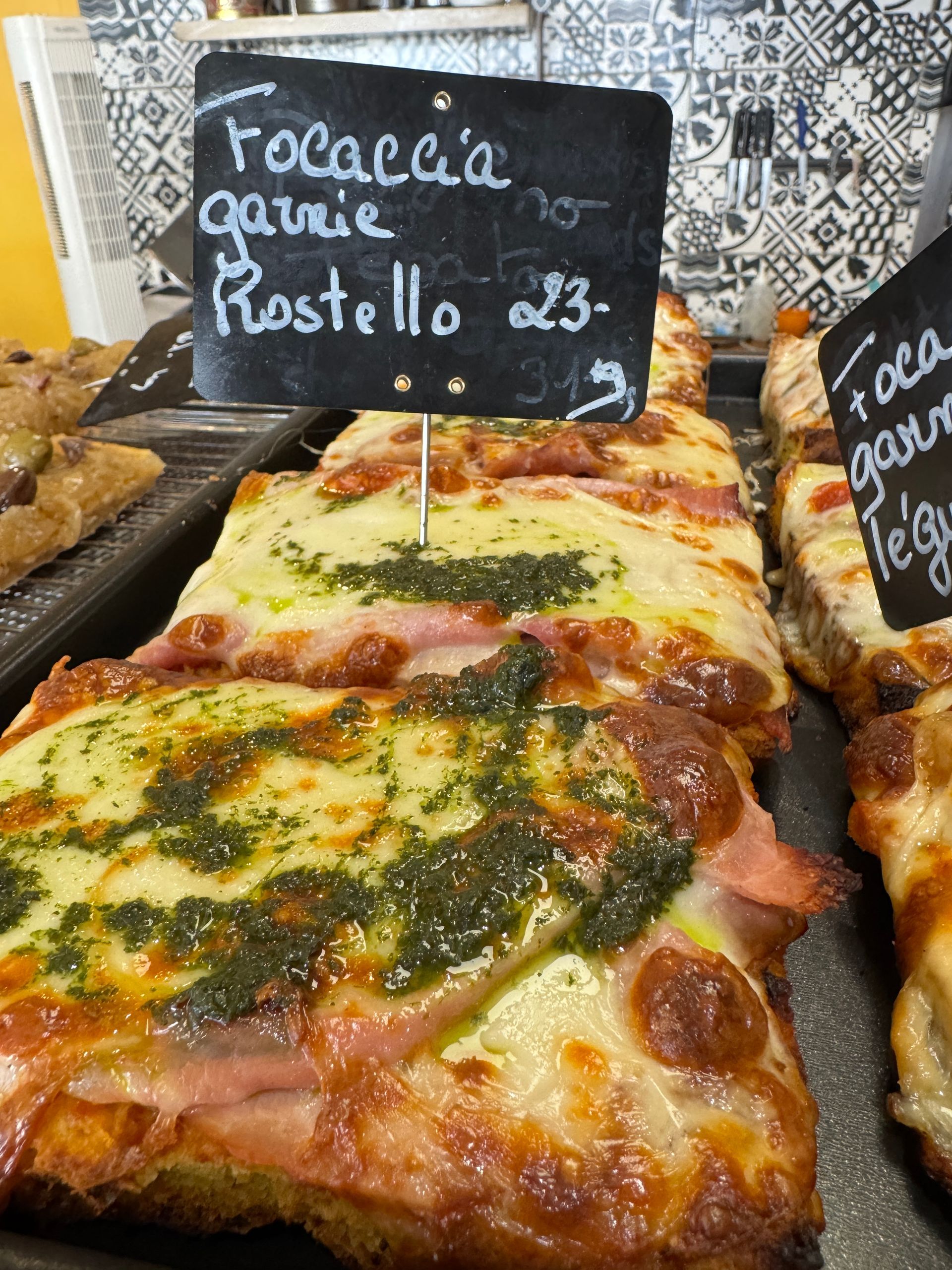 Focaccia garnie de pesto, de jambon et de fromage, servie dans un magasin.