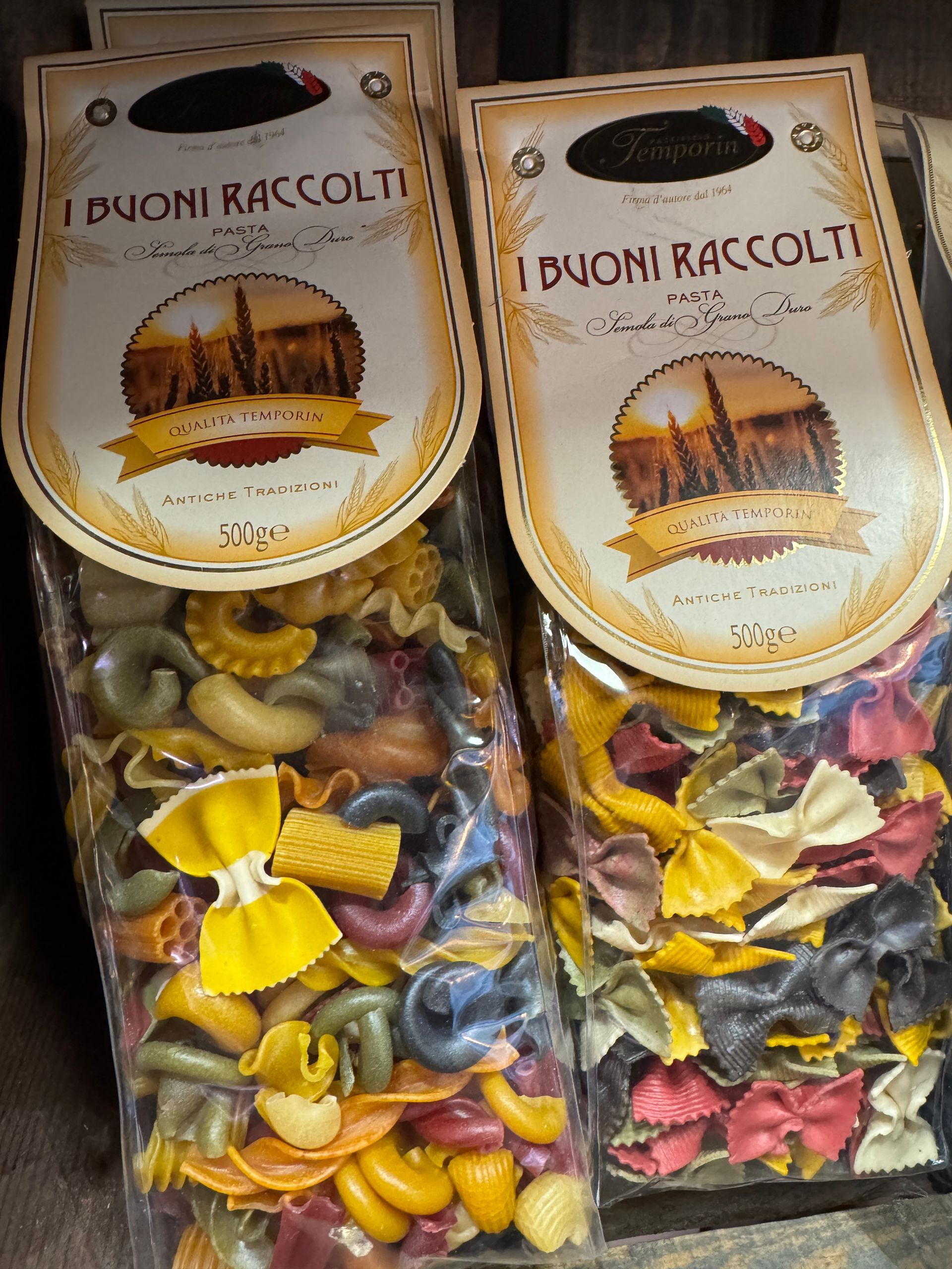 Deux sachets de pâtes colorées, étiquetés « I Buoni Raccolti », avec un motif de paysage urbain.
