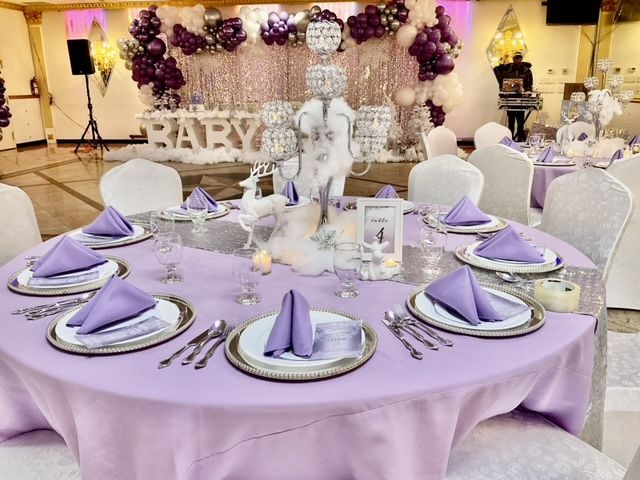 A table set for a baby shower with purple napkins and silverware.