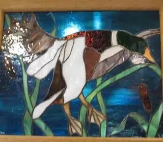 A stained glass painting of a duck swimming in the water.