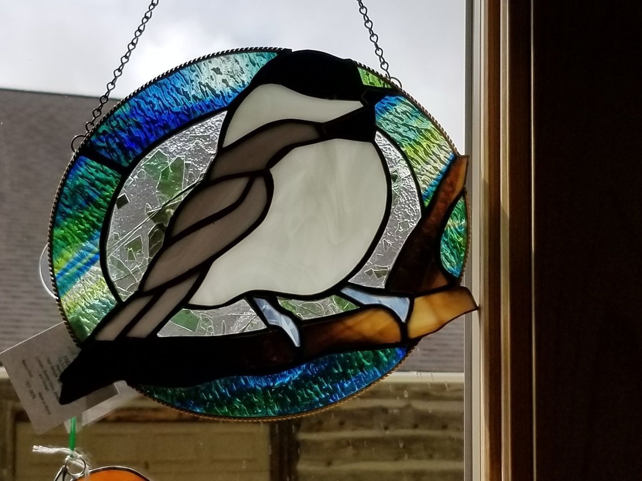 A stained glass painting of a bird sitting on a branch