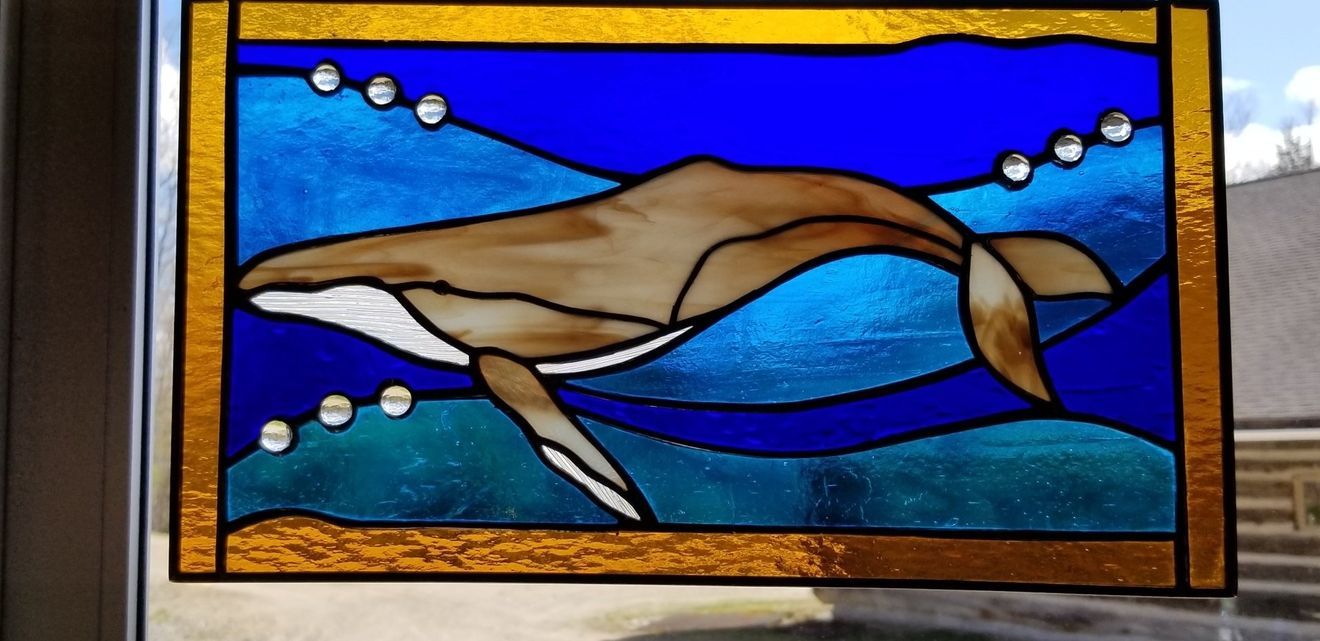 A stained glass painting of a humpback whale in the ocean.