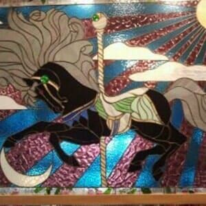 A stained glass painting of a horse on a merry go round.