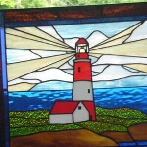 A stained glass painting of a lighthouse in the ocean