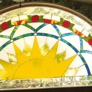 A stained glass window with a sun and flowers on it.