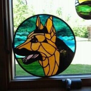 A stained glass picture of a german shepherd in a window