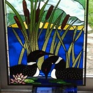 A stained glass window with two ducks in the water