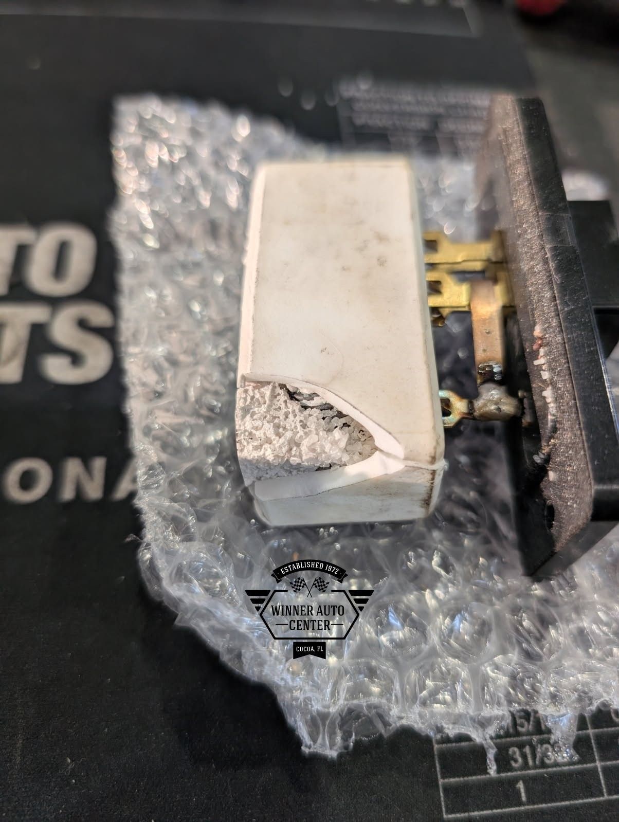 Close-up of a damaged white ceramic resistor with a broken corner | Winner Auto Center