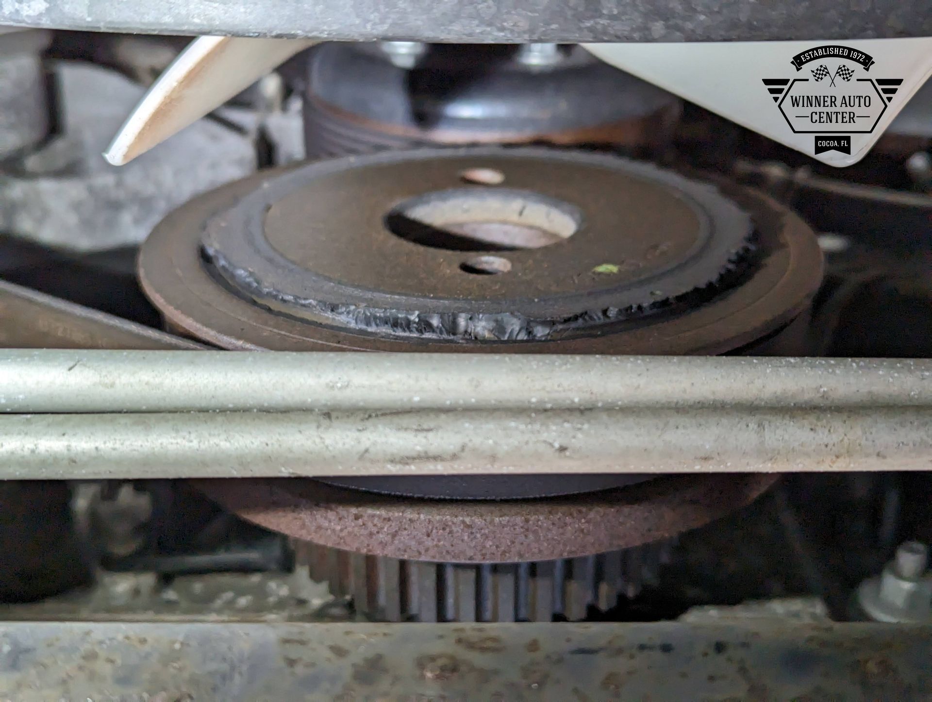 Close-up of a corroded car engine pulley with a fan blade visible above | Winner Auto Center