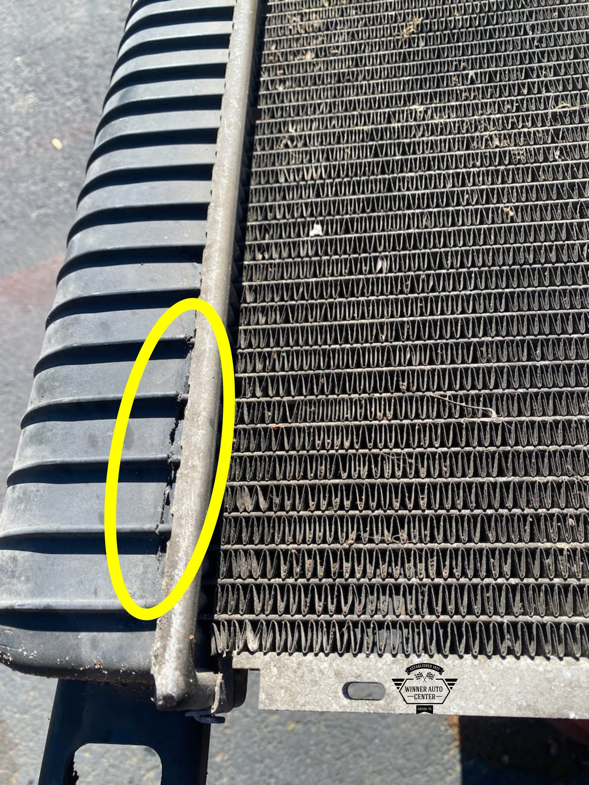 Close-up of a car radiator with a yellow circle highlighting a cracked seam | Winner Auto Center