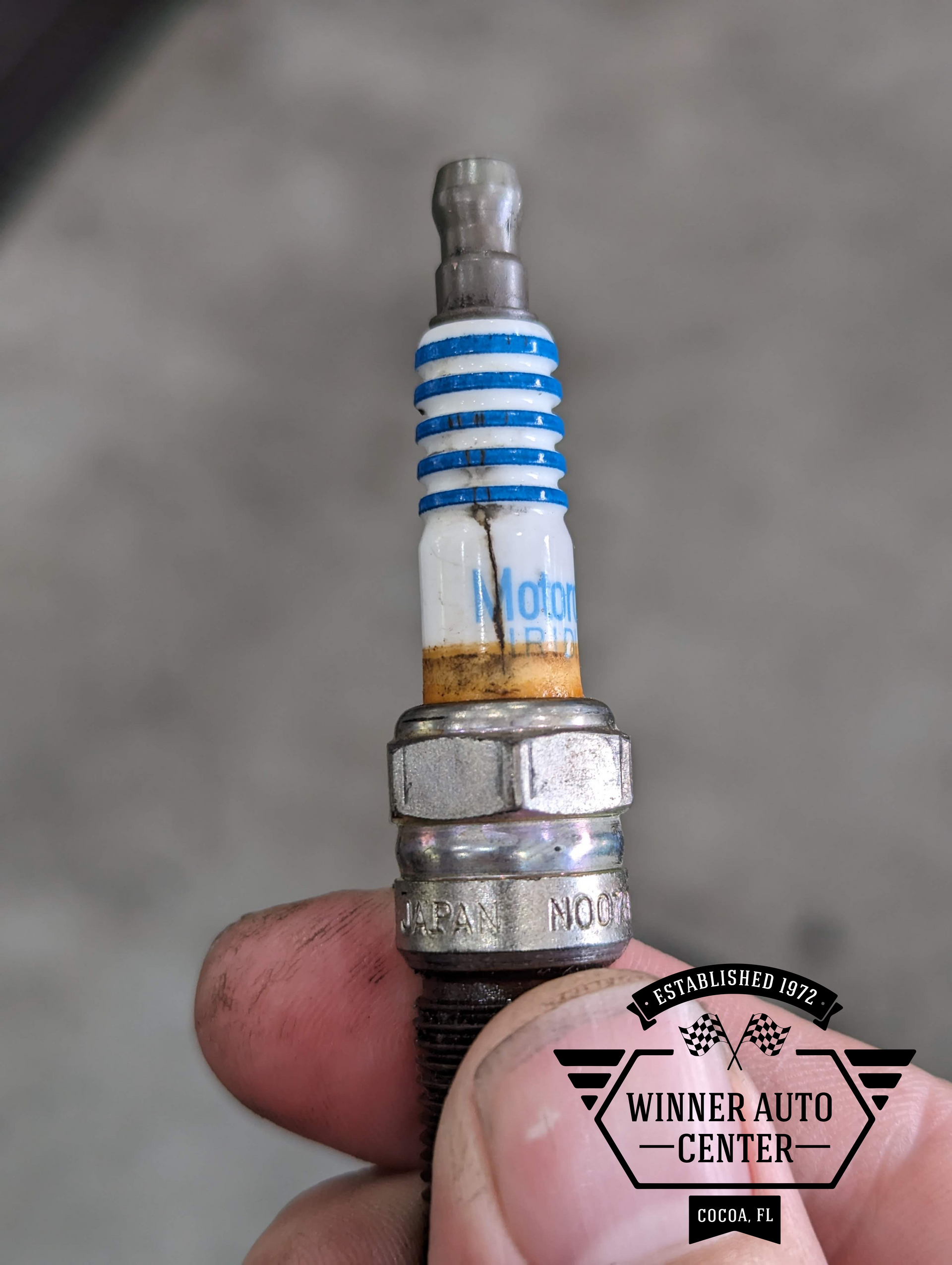 Close-up of a used spark plug held in hand | Winner Auto Center