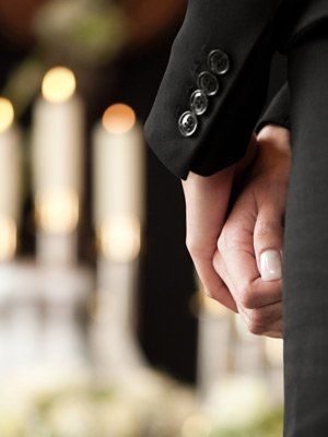 Loved ones hold hands at a virtual funeral service.