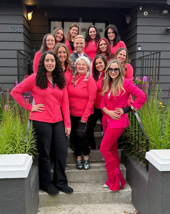 Group of people in red tops pose on steps of a building.