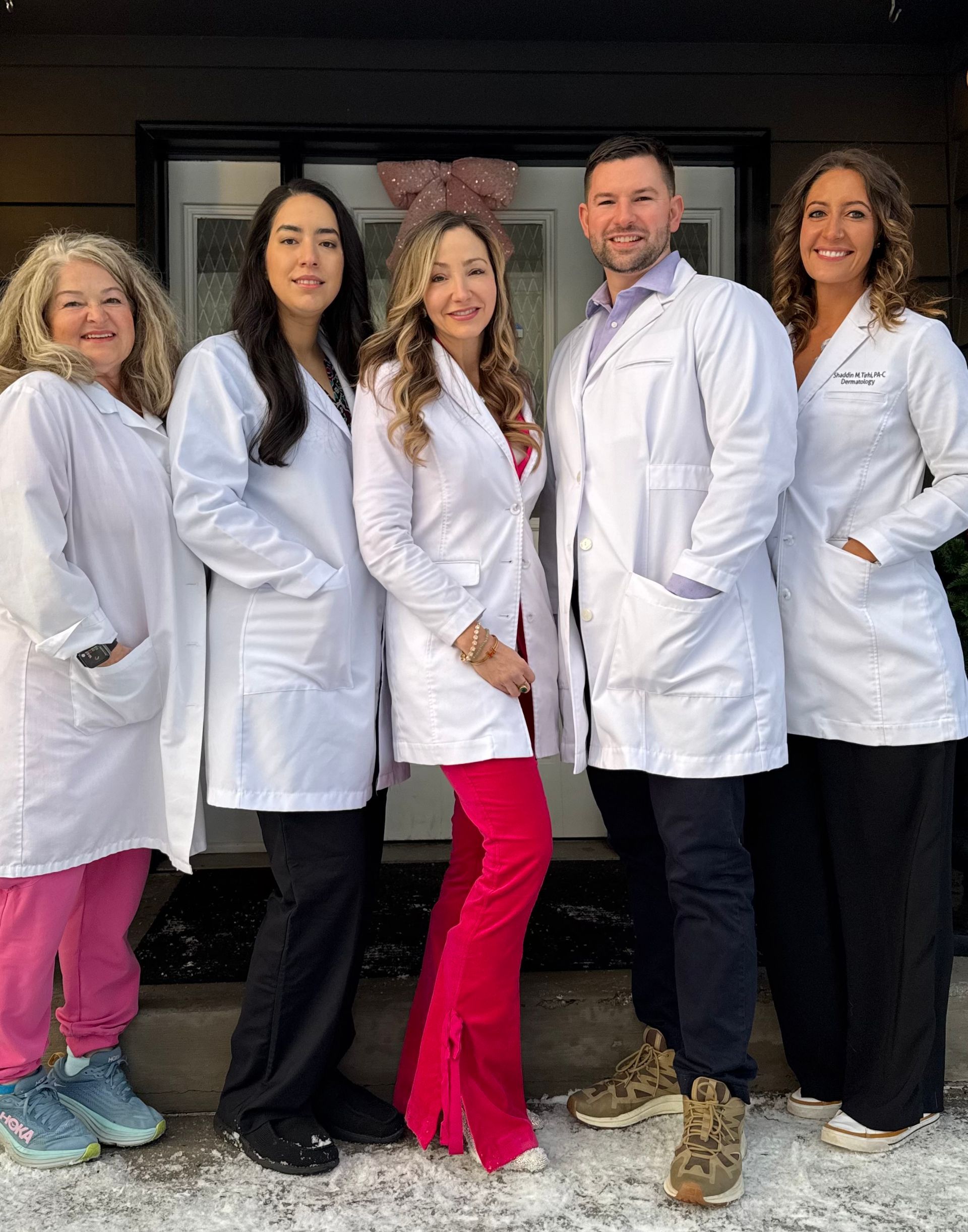 Group of people in red tops pose on steps of a building.