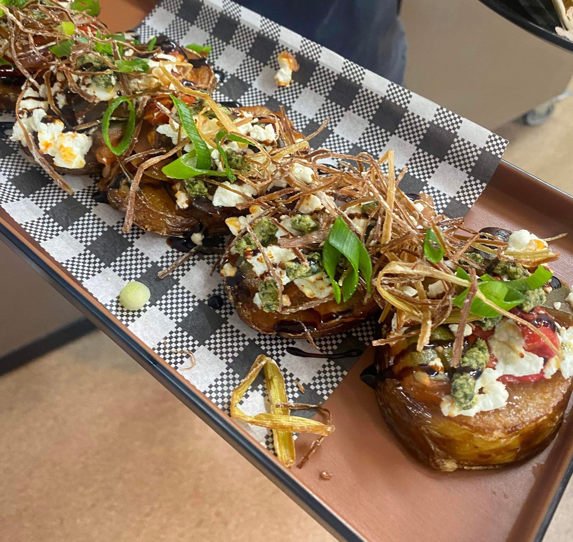 A person is holding a tray of food on checkered paper
