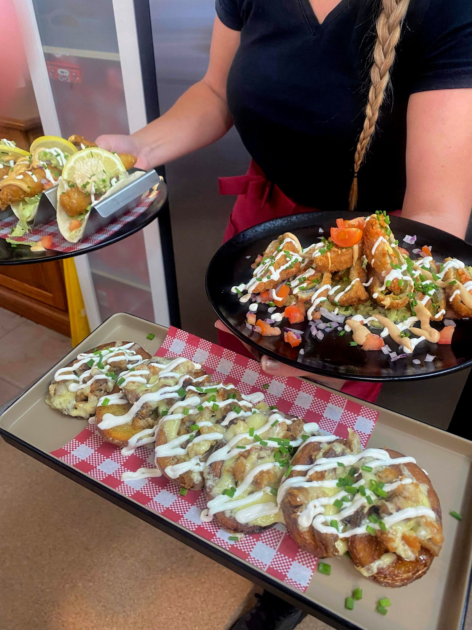 A woman is holding two plates of food on a tray.