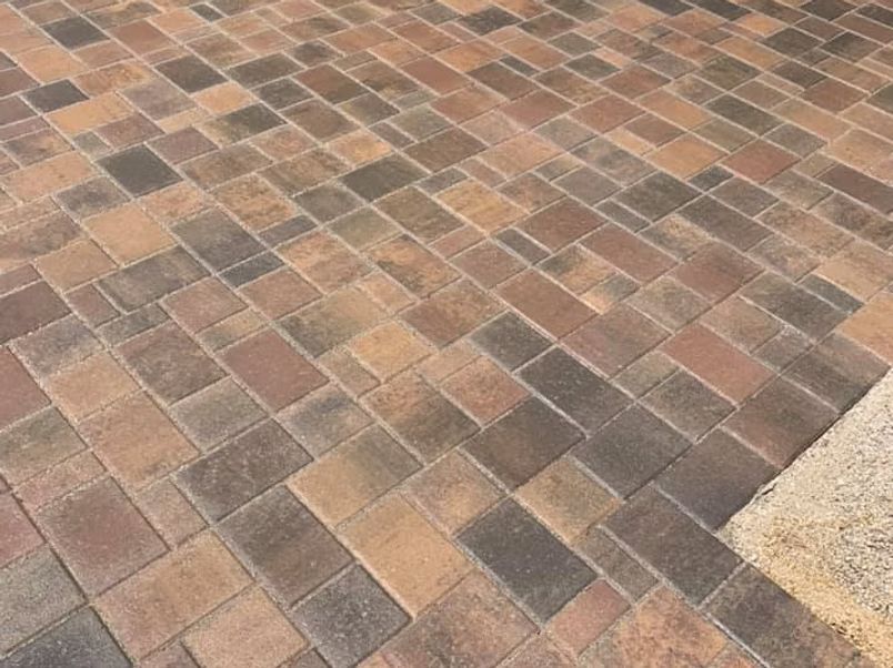 Multi-colored rectangular pavers in a herringbone pattern create a patio surface.