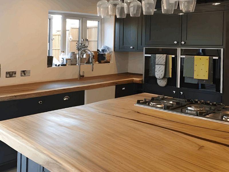 A kitchen with a wooden counter top and black cabinets