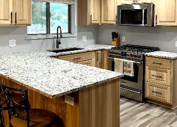 A kitchen with granite counter tops , stainless steel appliances , and wooden cabinets.