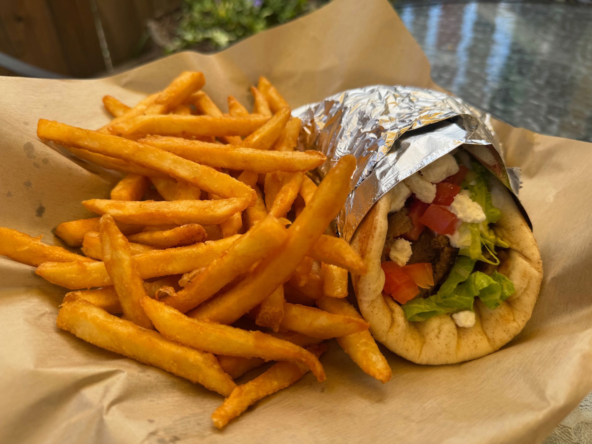 A gyro and french fries on a plate on a table.