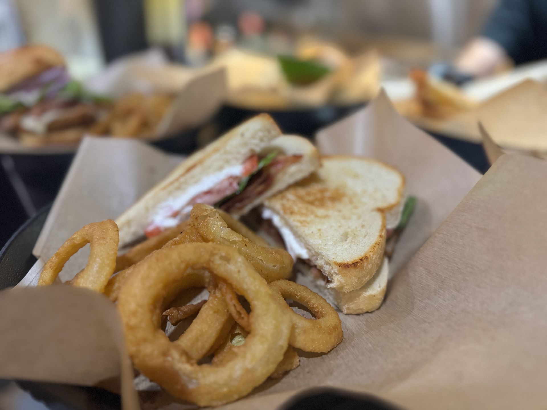 A close up of a sandwich and onion rings on a table.