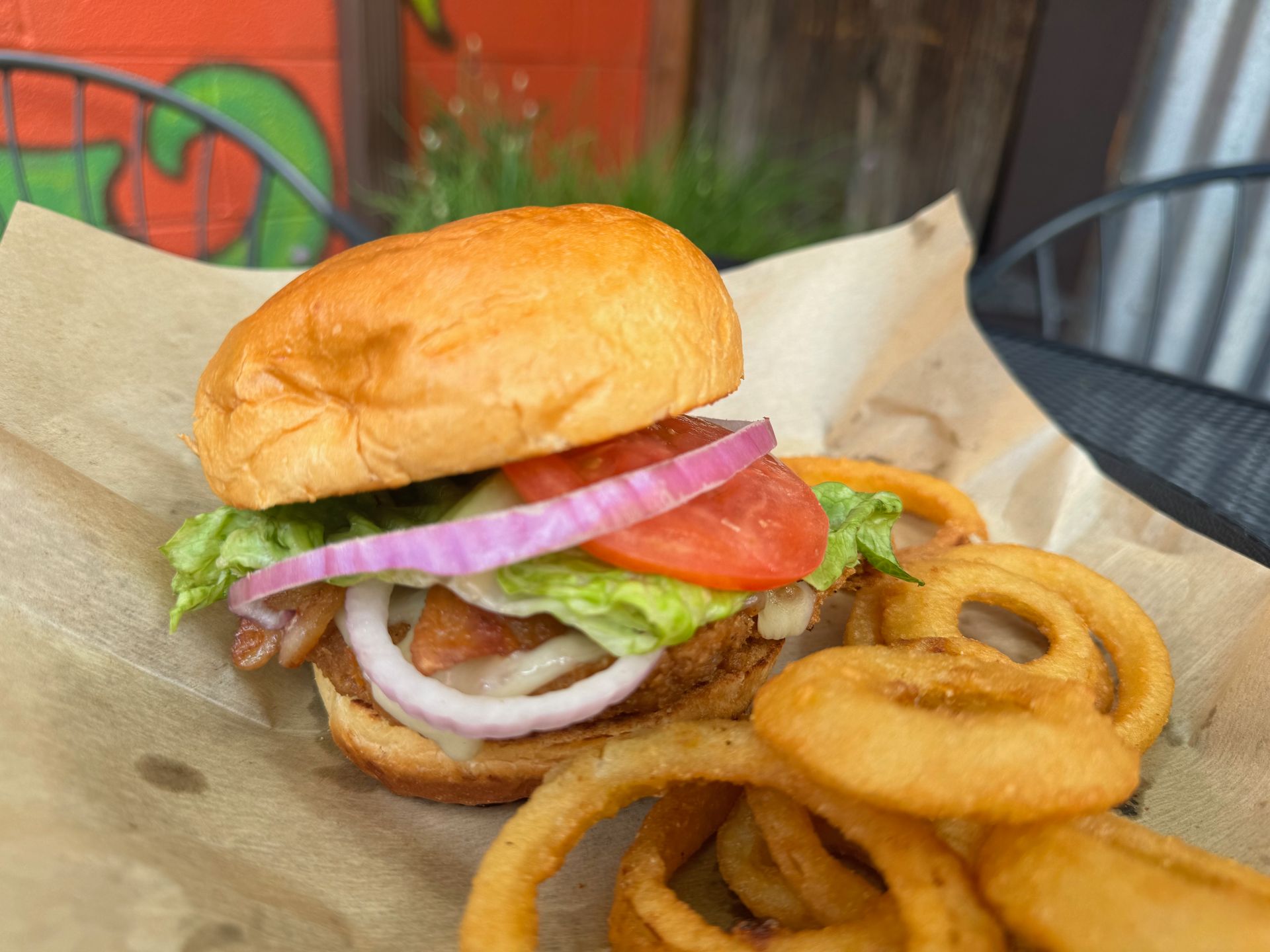 A close up of a hamburger and onion rings on a table.