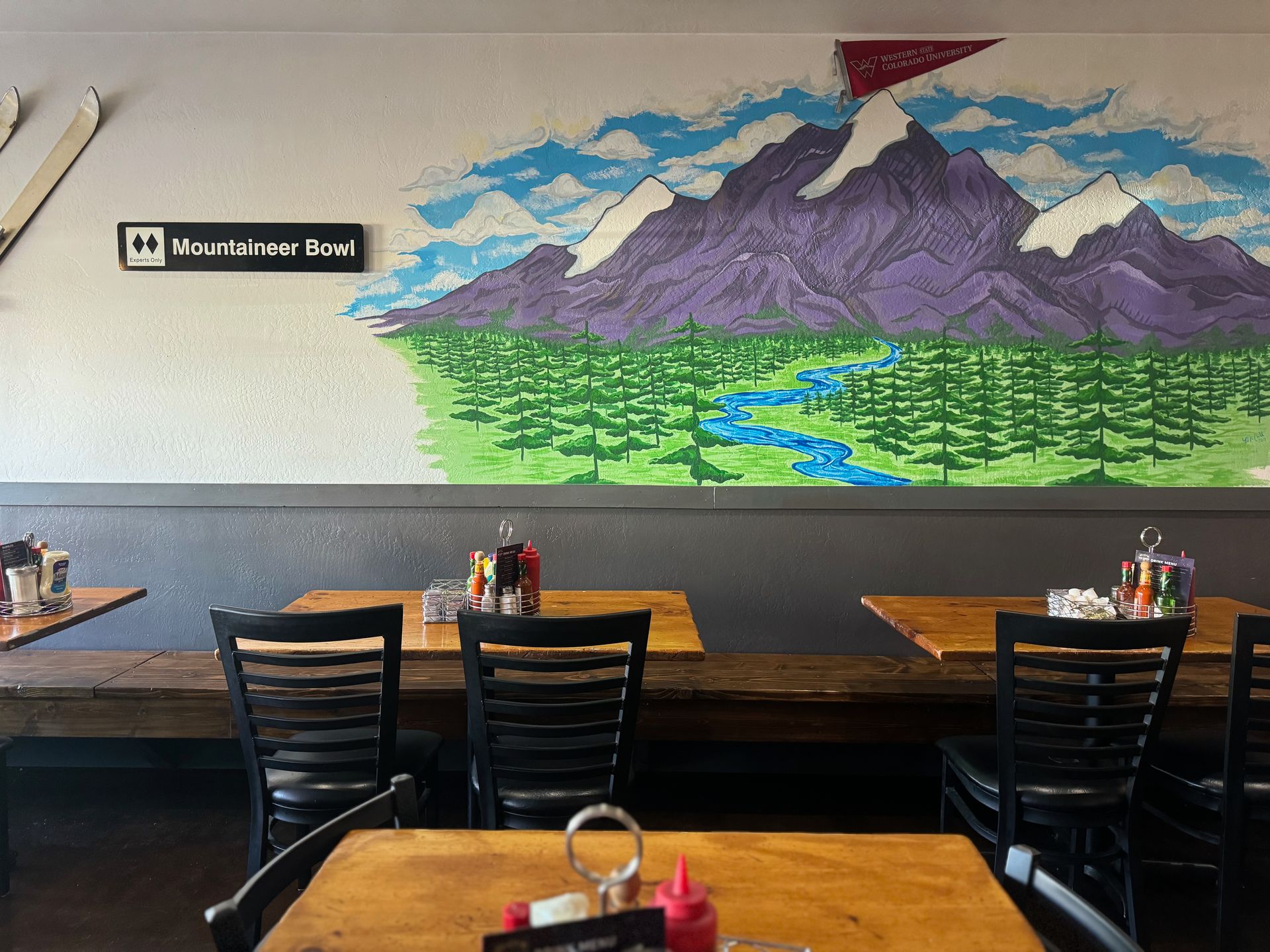 A restaurant with tables and chairs and a mural of mountains on the wall.