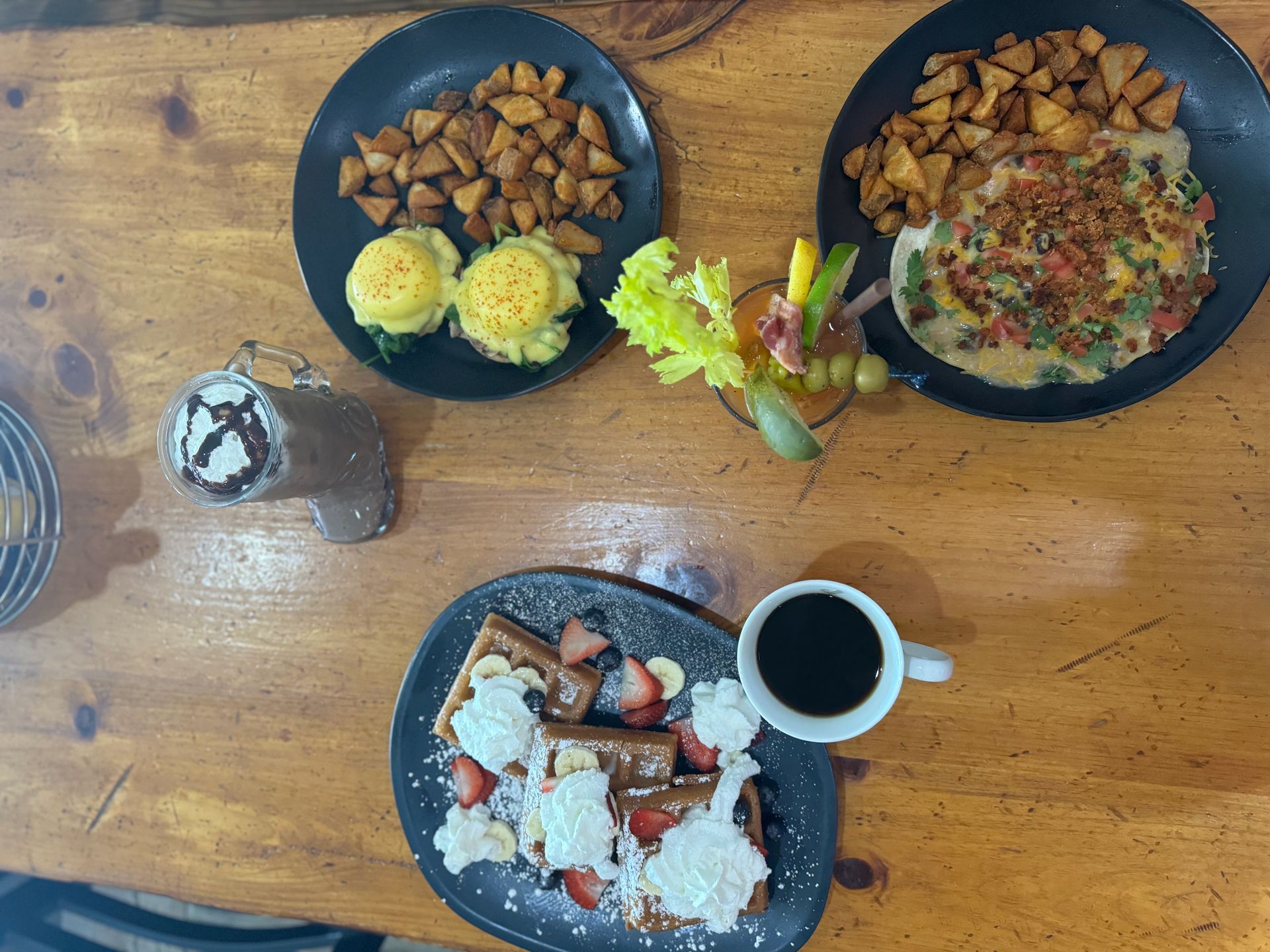 A wooden table topped with plates of food and a cup of coffee.