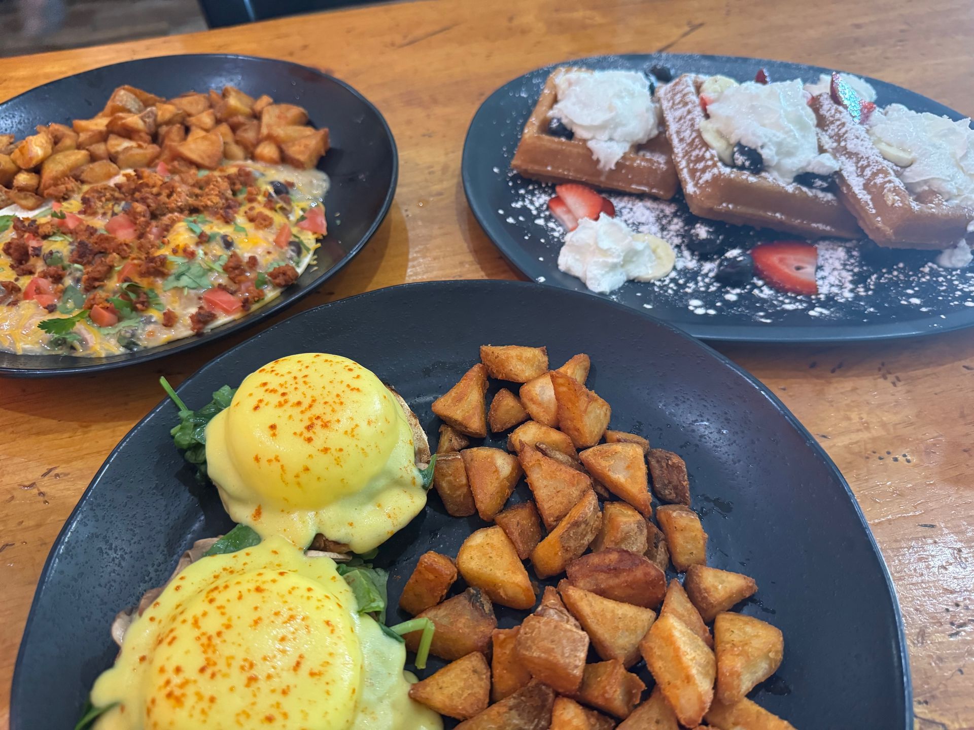 Three plates of food are sitting on a wooden table.