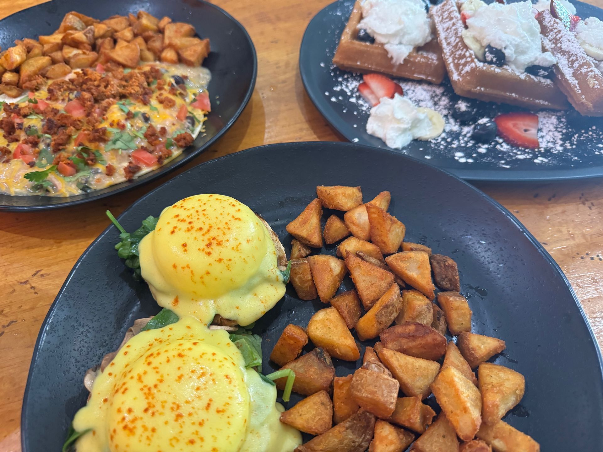 Three plates of food are sitting on a wooden table.