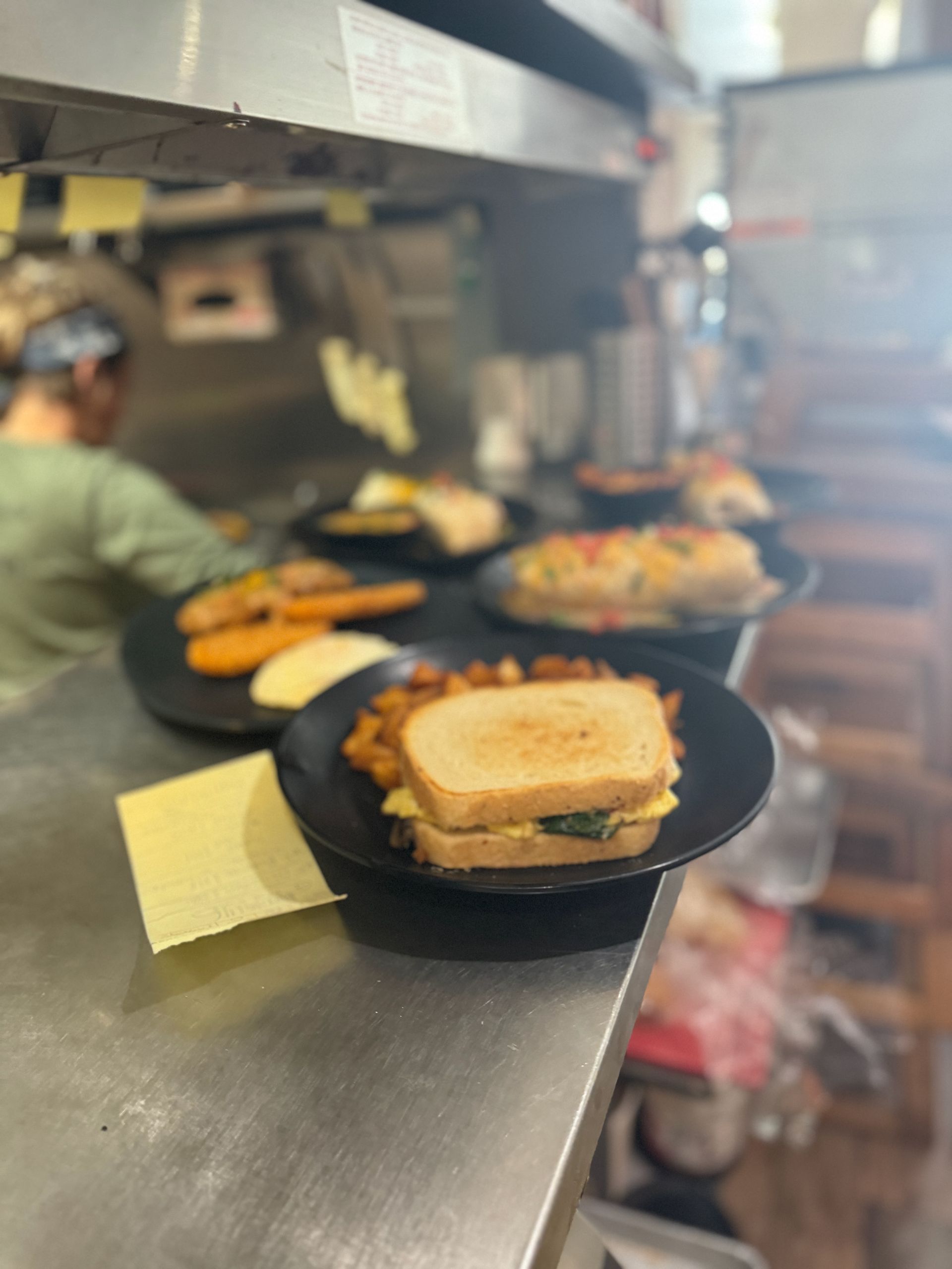 A sandwich is on a plate on a counter in a kitchen.