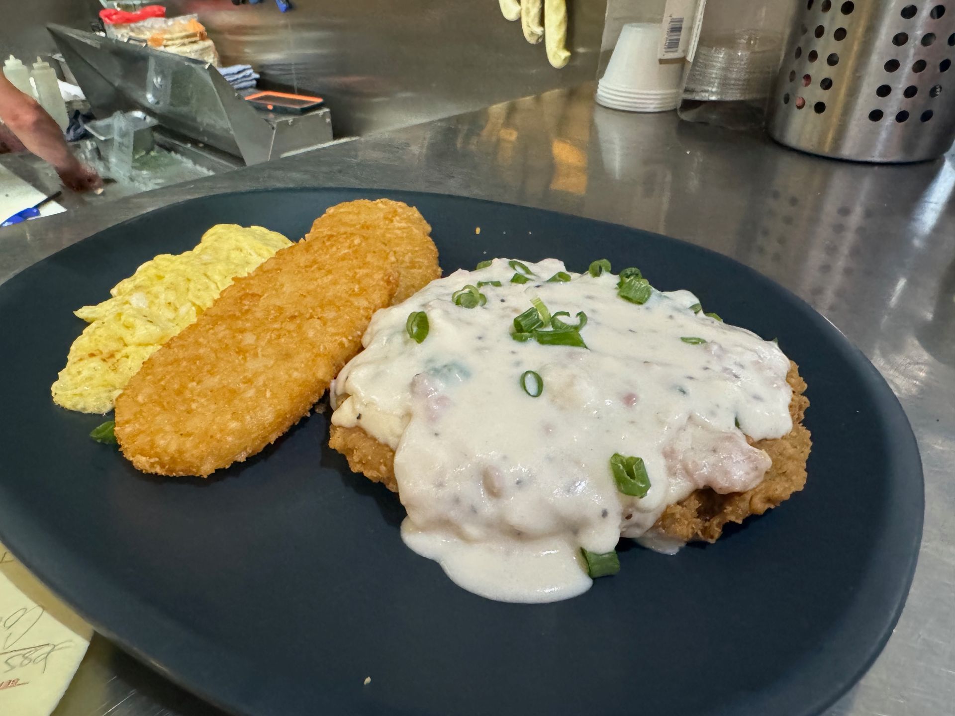 A black plate topped with fried food and gravy on a counter.