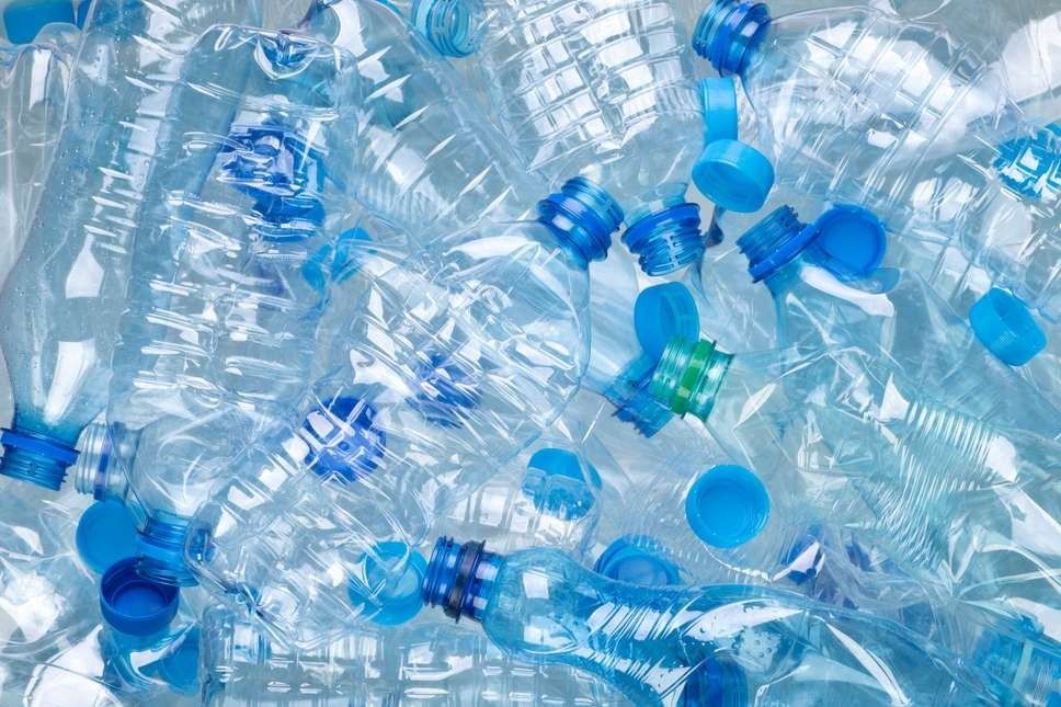 Pile of clear plastic water bottles and blue caps, suggesting recycling.