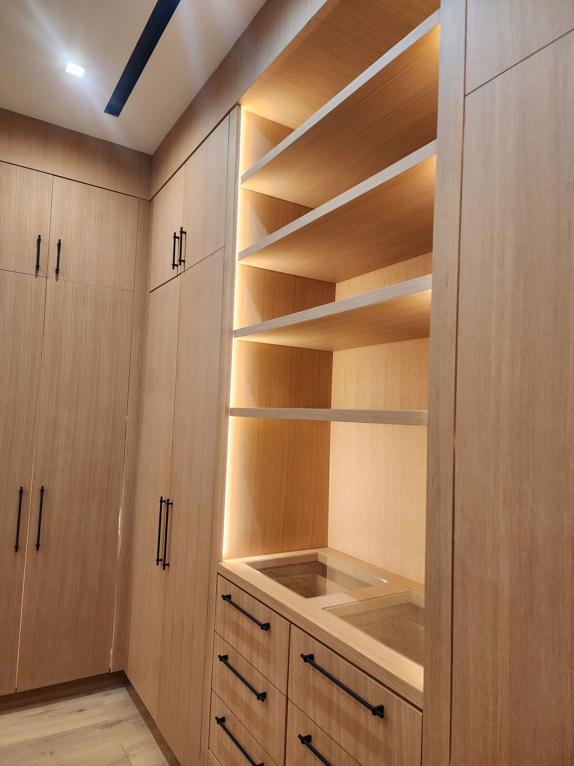 Wooden closet with shelves, drawers, and integrated lighting.
