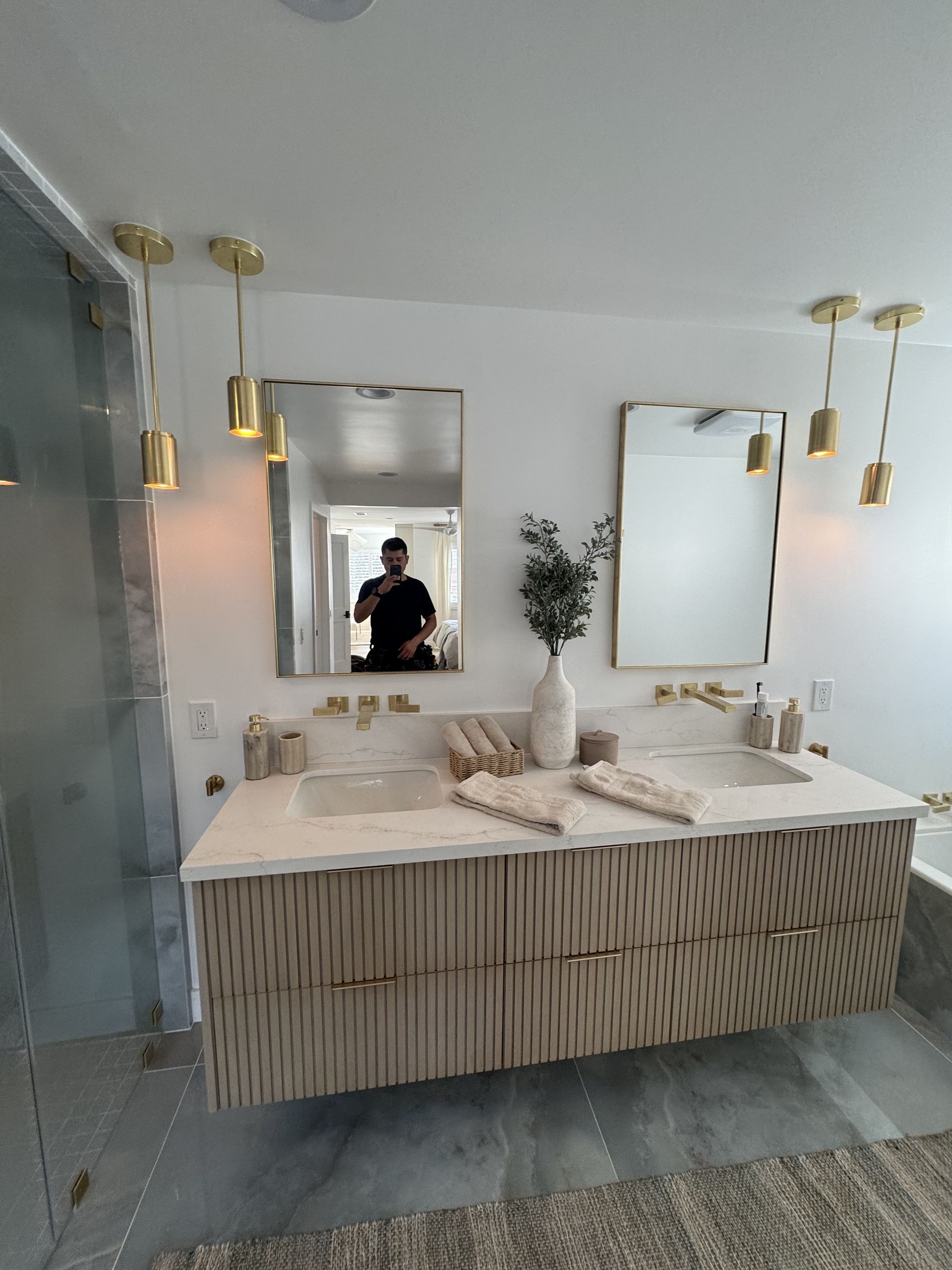 Modern bathroom with floating double vanity, two mirrors, and pendant lights.