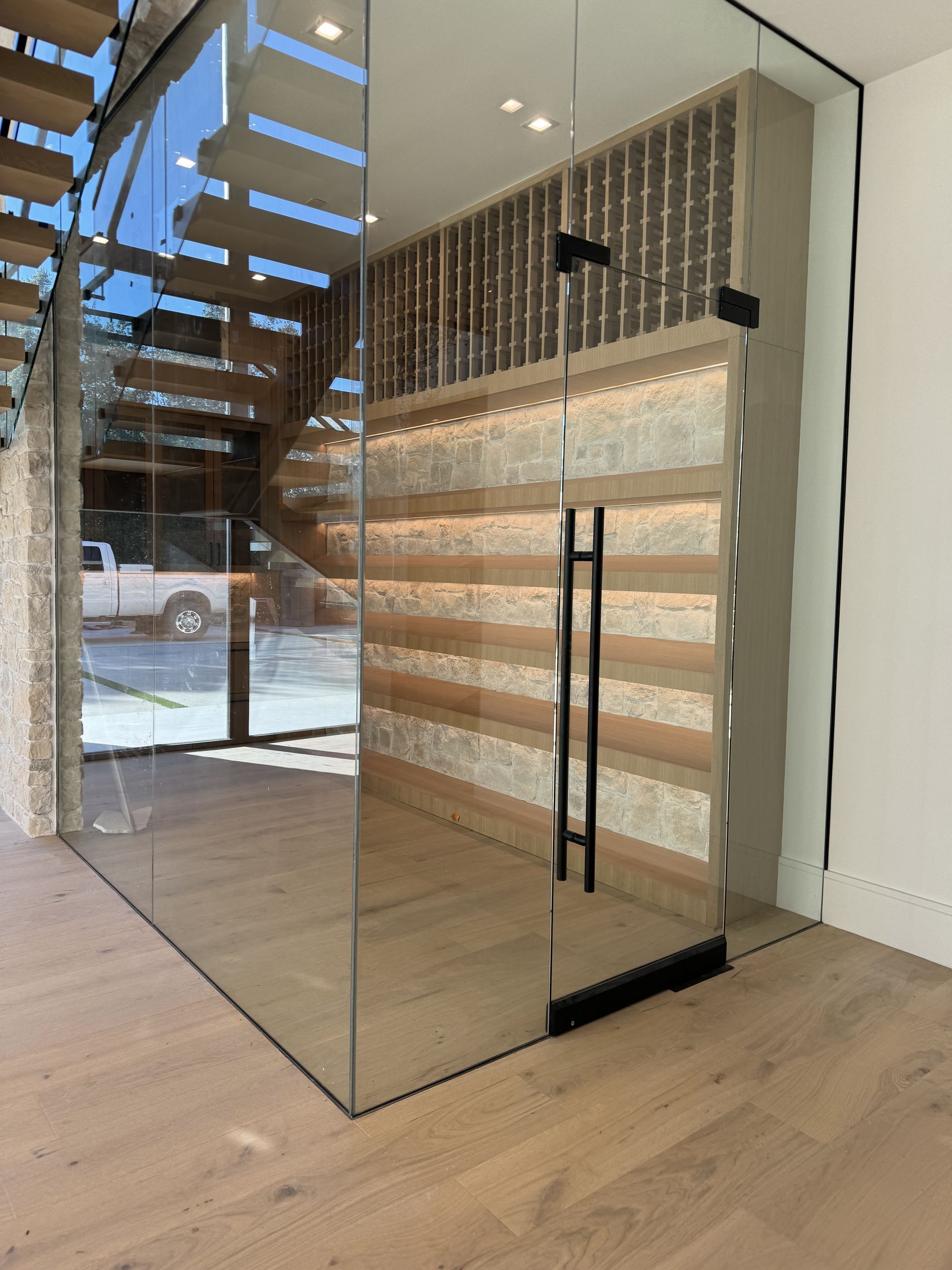 A wine cellar with a glass wall and stairs in the background.