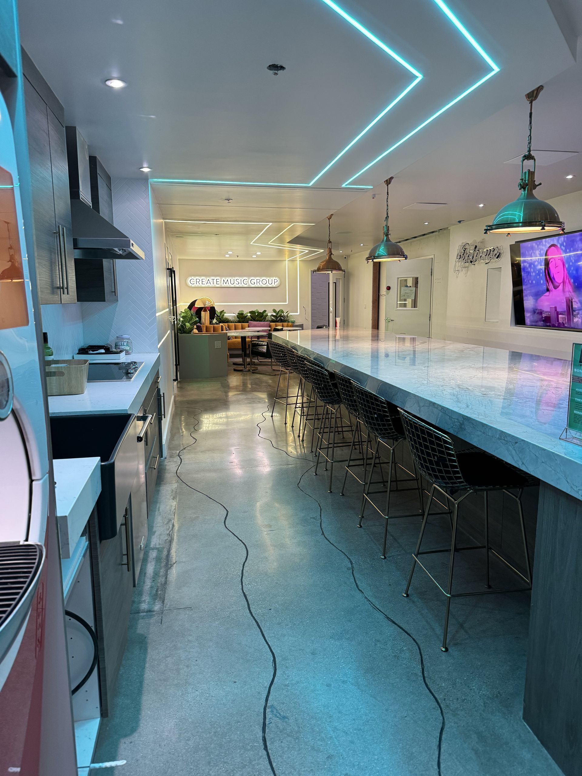 A kitchen with a long counter and a television on the wall.