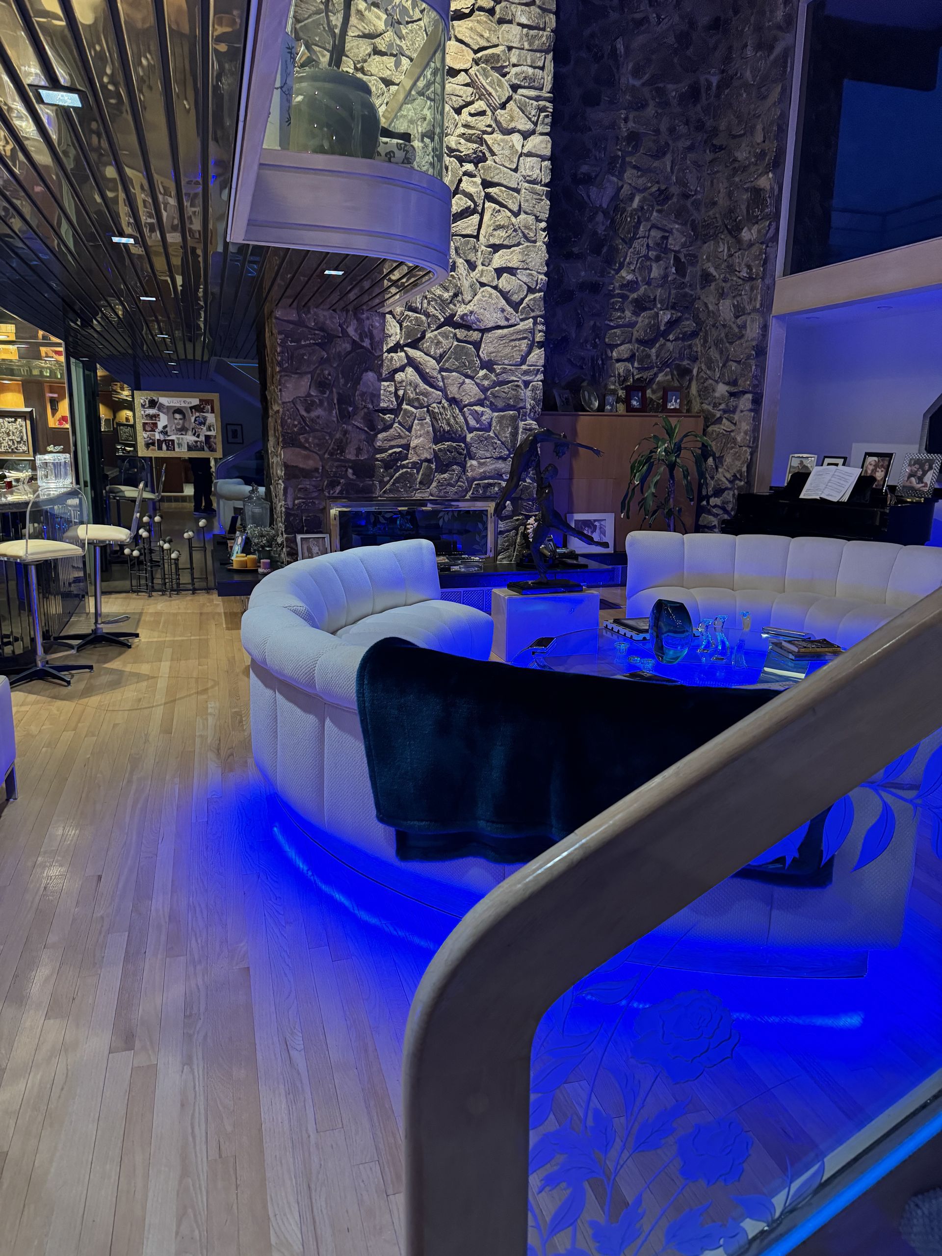 Luxurious interior with curved white sofas, blue lighting, and a stone fireplace.