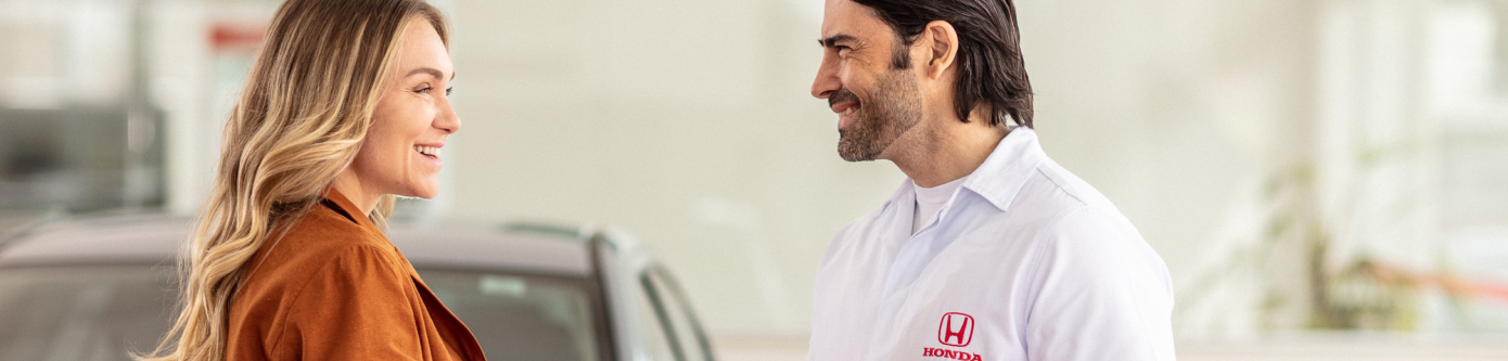 Um homem e uma mulher estão um ao lado do outro na frente de um carro.