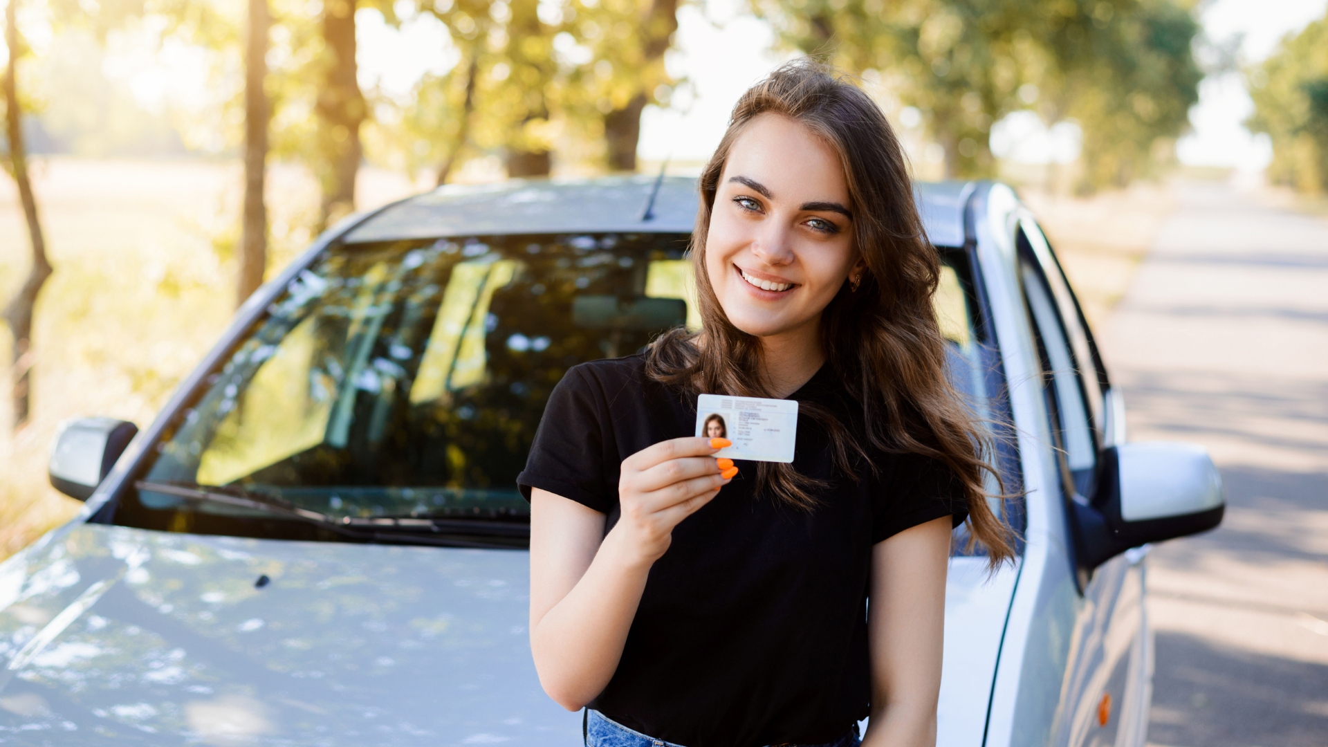 Uma mulher tem carteira de motorista na frente de um carro.